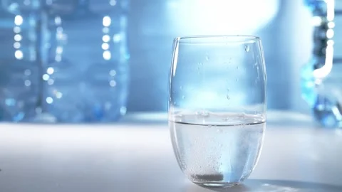 White effervescent tablet dissolving in glass of water over blue background. Video stock 311023877