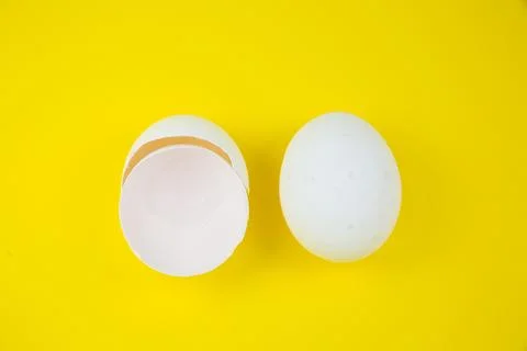 White egg and eggshell on the yellow background. Copy space. Minimalism, or.. Stock Photos