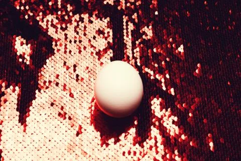 White egg on background of sequin. Stock Photos