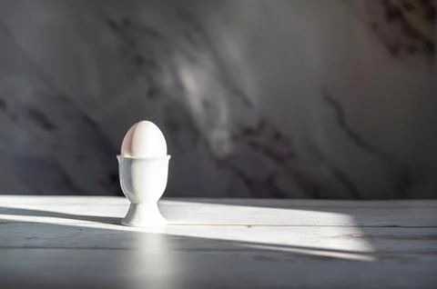 White egg in ceramic egg cup for breakfast. Holder stand for boiled or raw Stock Photos