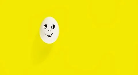 White egg with cheerful face on yellow background Stock Photos