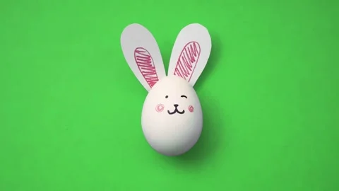 White egg with cute rabbit face on green background Stock Footage 289797642