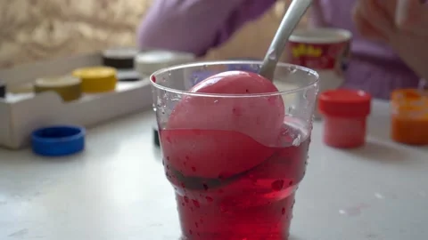 White egg dipped in a glass of red water and stained. Preparation for Easter Video stock 103170416