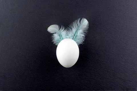 White egg with ears on a black stone background.Minimalism.Place for text Stock Photos