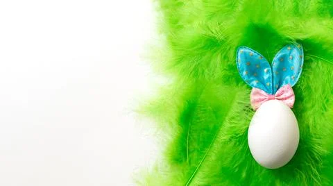 White egg with Easter Bunny ears on a green soft gentle feather background, c 스톡 사진