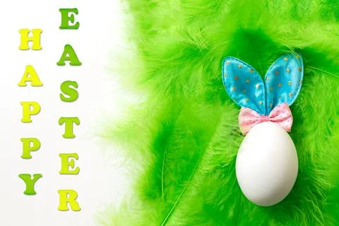 White egg with Easter Bunny ears on a green soft delicate feather background  스톡 사진