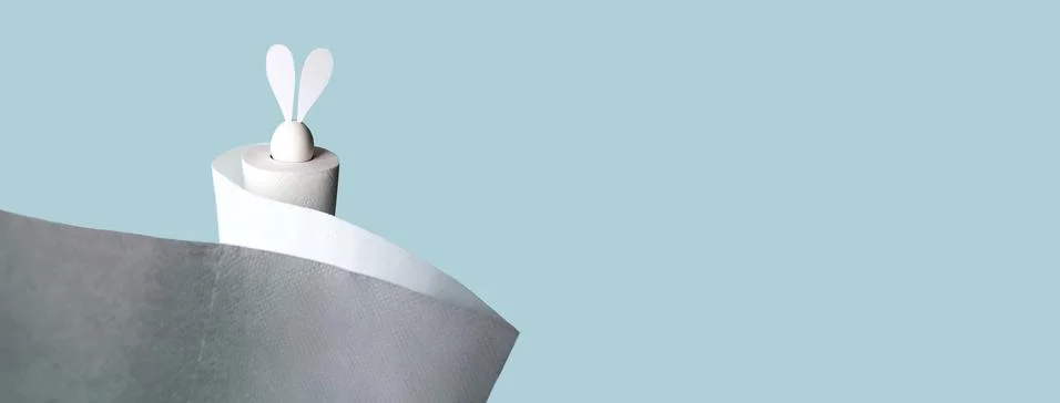 White egg with hare ears in a roll of toilet paper. Hard shadow on a light ba Photos