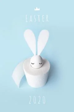 White egg with hare ears in a roll of toilet paper. Hard shadow on a light Stock Photos