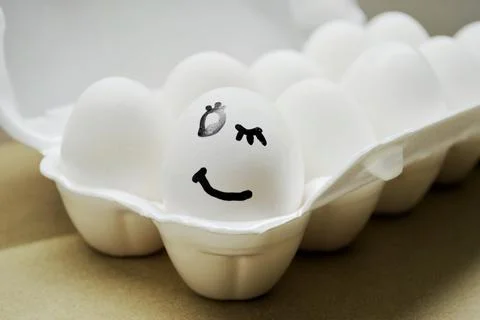 White egg with painted smiling face in the tray Stock Photos