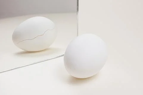 White egg reflected in mirror showing cracked shell Stock Photos