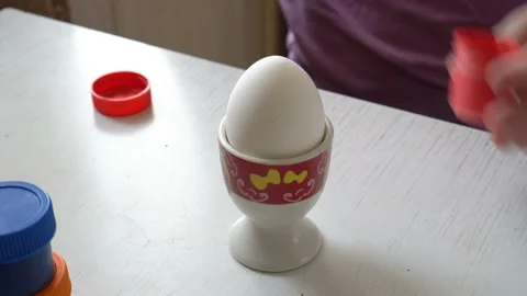 White egg stands on a stand on the table, and the child begins to draw on it 스톡 동영상 103154773