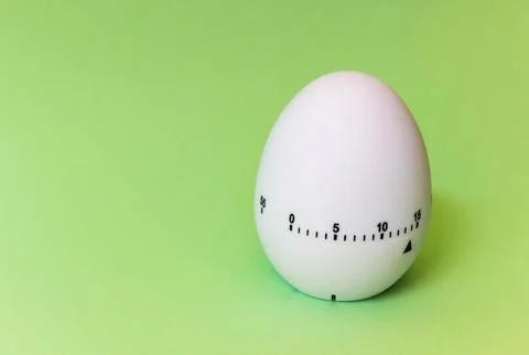 White egg timer on green background. Happy Easter in the kitchen. Home relate Stock Photos