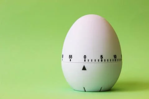 White egg timer on green background. Happy Easter in the kitchen. Home relate Stock Photos