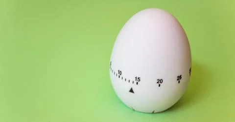 White egg timer on green background. Happy Easter in the kitchen. Home relate Stock Photos