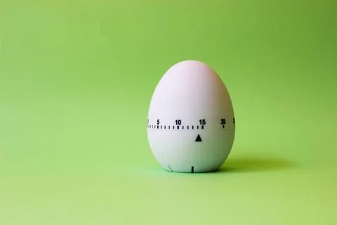 White egg timer on green background. Happy Easter in the kitchen. Home relate Stock Photos
