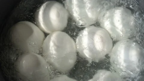 White eggs are boiled in boiling water in a metal pan. One egg cracked. Video stock 88289075
