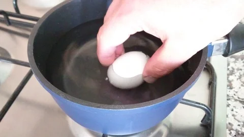 White Eggs Are Boiled In Boiling Water In A Metal Pan. One Egg Cracked. Stock Footage 91665926