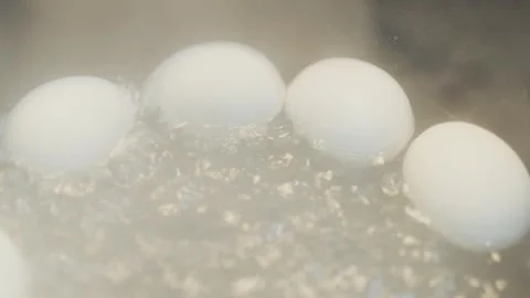 White eggs boiling in bubbling water for breakfast Stock Footage 332803609