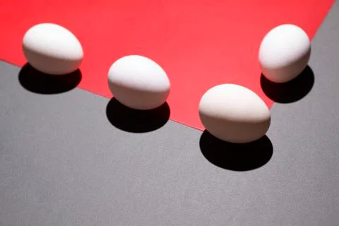 White eggs on the border of a red triangle on a gray background Stock Photos