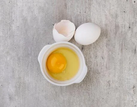 White eggs with broken egg over grey background Stock Photos