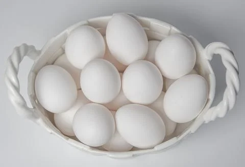 White eggs in a ceramic white corp on white background Stock Photos