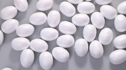 White eggs on a gray background. Lots of objects are spinning. View from above Stock Footage 153871881