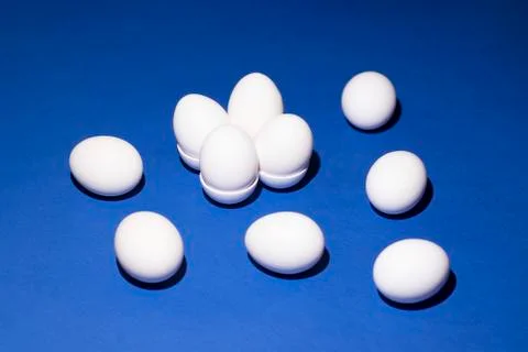White eggs lie in the egg shape and randomly on a blue background Stock Photos