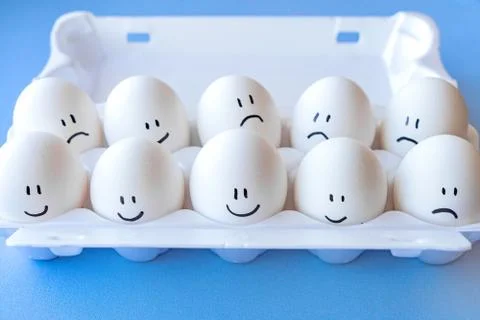 White eggs in a package on a blue background close-up Stock Photos