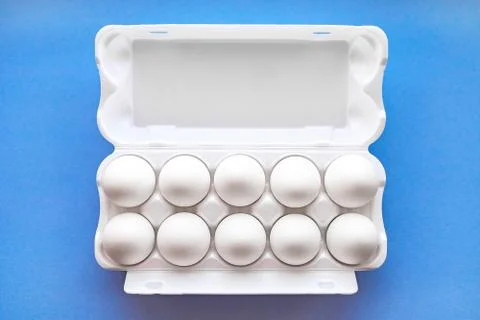 White eggs in a package on a blue background close-up view from above. Foto stock