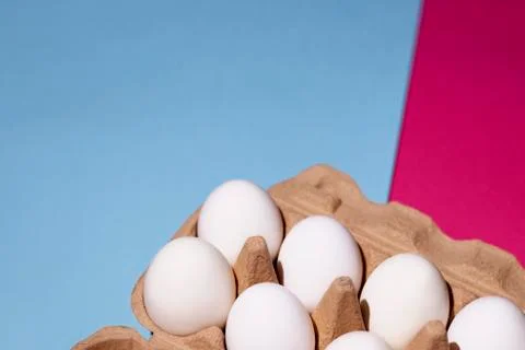 White eggs in the package on the right of a blue-pink background Stock Photos