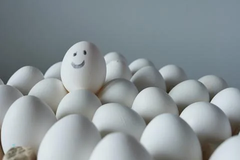 White eggs with smiley face on grey background. Close up. Stock Photos
