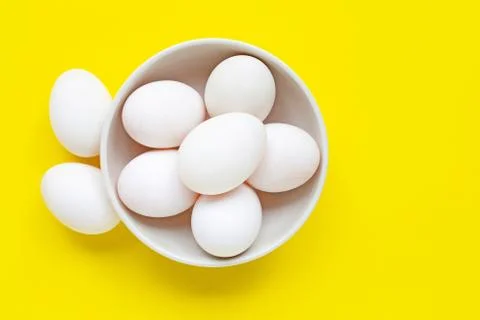 White eggs on yellow background. Stock Photos