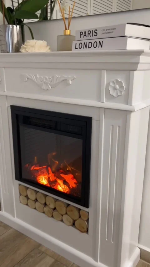 White electric fireplace mantel with elegant shelf decor and glowing flame Stock Footage 341701151