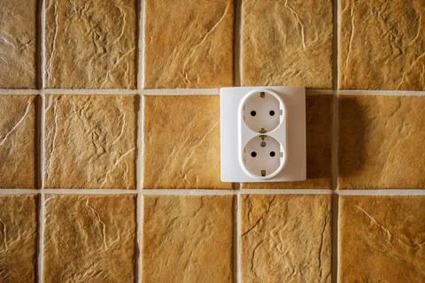White electric socket on kitchen wall with ceramic tiles Stock Photos