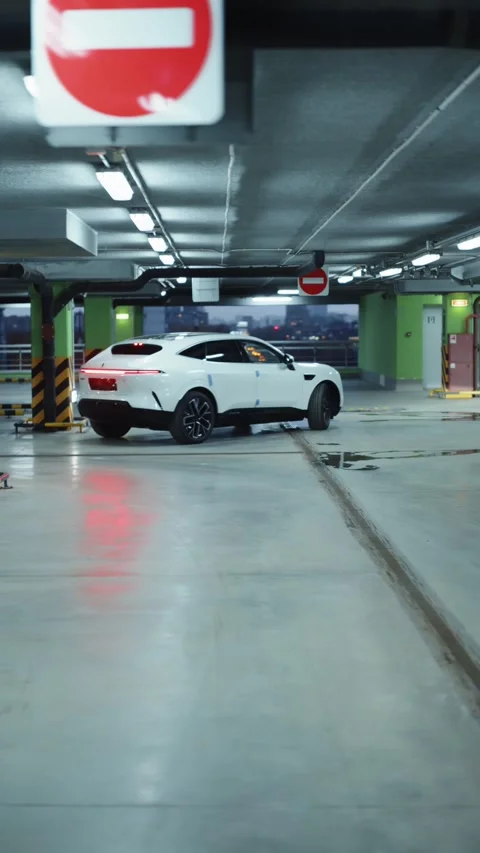 White electric SUV exiting underground parking garage 스톡 동영상 318417909
