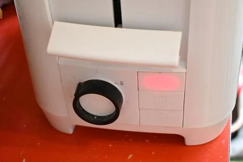 White electric toast maker on a red surface Photos