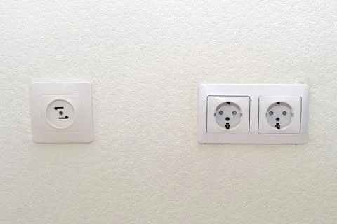 White electrical outlet and double socket on a textured wall. Household build Stock Photos