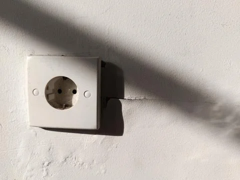 A white electrical outlet mounted on a white wall. Stock Photos