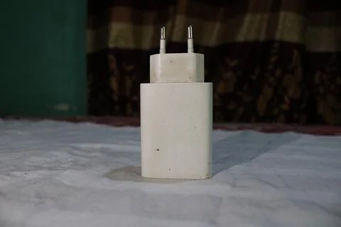 White electrical power adapter with two pins on a bed sheet in a room  elec.. 写真素材