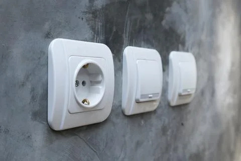 White electrical power socket and two light switches mounted on a raw polis.. Stock Photos