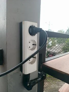 White electrical power strip attached to a wall with a black power cable pl.. Stock Photos