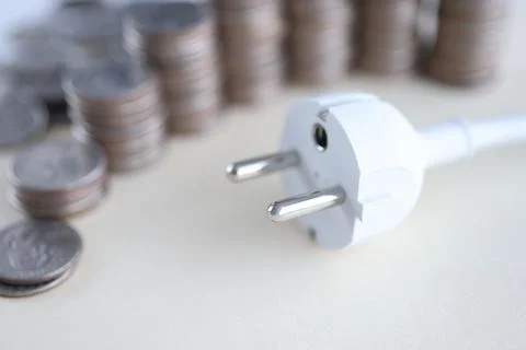White electrical socket with coins lie on table Foto stock