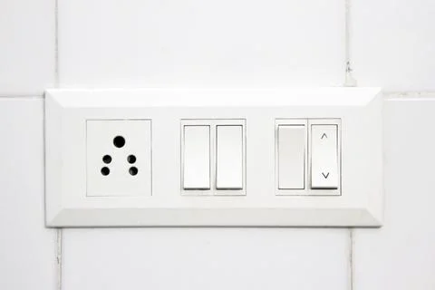 White electrical switch panel and plug point on white tiled wall Stock Photos
