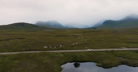 White electro car passing breathtaking moody landscape with spacious fields and Stock Footage 288743854