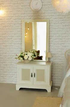 White elegant bedside table with square mirror located in bedroom Stock Photos