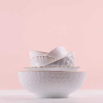White elegant plates in stack with thin golden bezel, bizarre texture on whit Stock Photos
