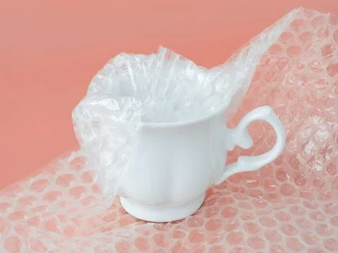 White elegant tea cup half packaged with white transparent bubble wrap Stock Photos