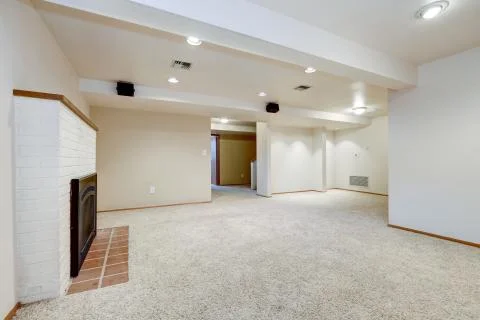 White empty basement room with fireplace and wall to wall carpet floor. North Stock Photos