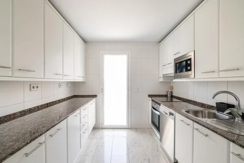 White empty classic kitchen with lots of cabinets with large marble countertop Photos