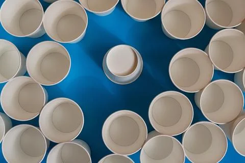 White empty cups surround one cup, which is turned upside down, not like ever Stock Photos